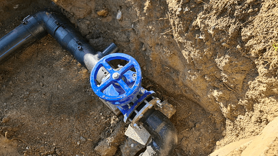 Blauer Wasserhahn zur Kontrolle des Abwassersystems im Boden